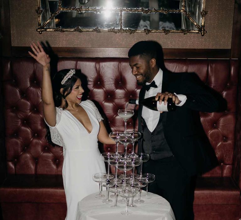 Bride and groom at elegant Manor House wedding doing wedding champagne tower photoshoot 