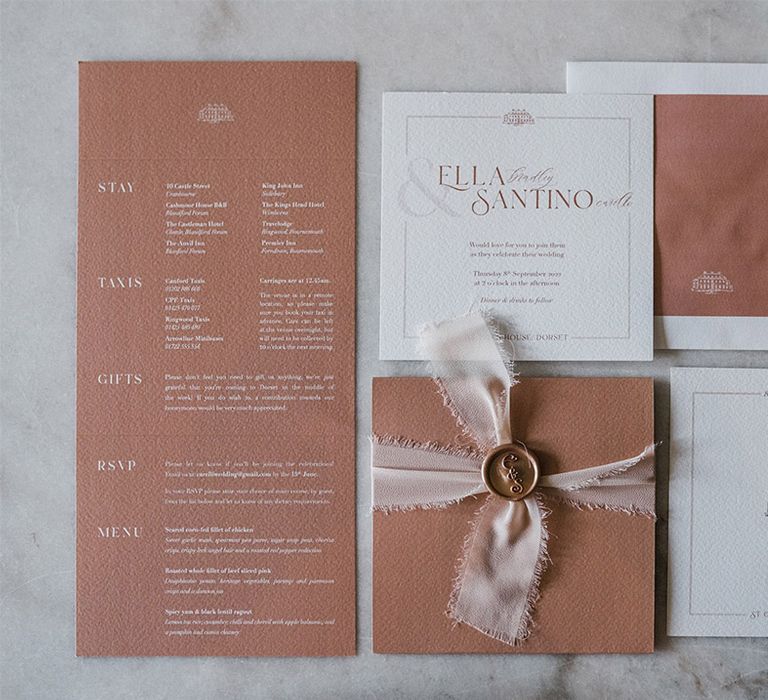 Pink and white stationery flatlay including wedding invitation, save the date, and order of the day details 