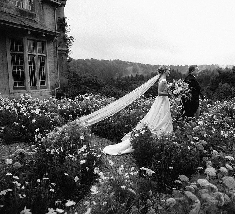 The bride and groom walk along together in the gardens of the hotel wedding venue 