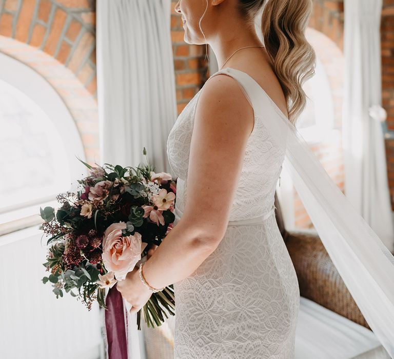 Bride in Karen Willis Holmes wedding dress with her blonde hair in a sleek ponytail wedding hairstyle 