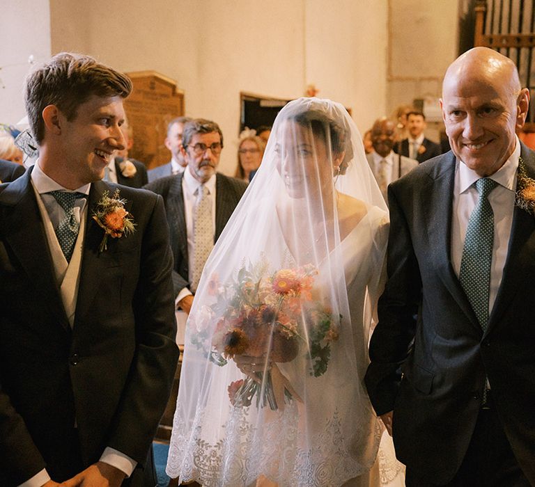 A traditional Coombe Trenchard and church wedding with the bride holding a colourful bouquet 