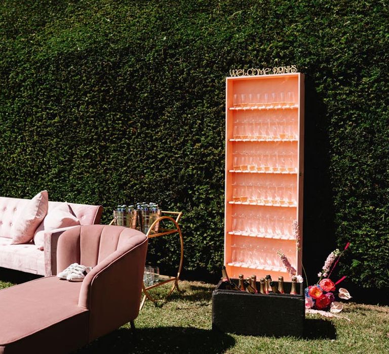 Pink and blue wedding seating area inspired by Morocco with sofas, champagne, and pink glasses for guests 