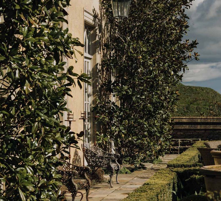 Euridge Manor wedding venue garden with large foliage columns and brass benches 