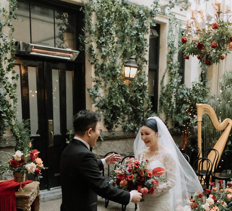 Bride in Pronovias mermaid wedding dress with groom in black tuxedo having their first look moment together 