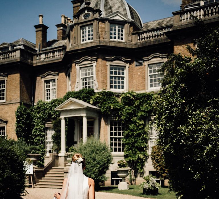 Bride in stunning and traditional sleeveless wedding dress walking up to the Surrey wedding venue 