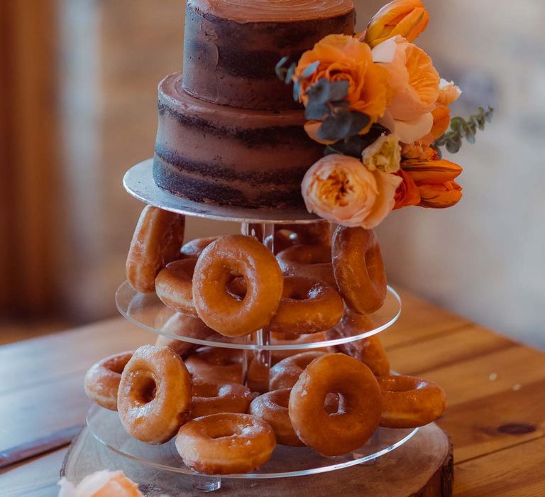 Donut tower wedding cake with laser cut wedding cake topper and orange garden rose cake decorations at Kingscote Barn Tetbury 