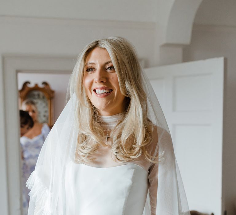 Bride in strapless gown with mesh overlay top and ruffle embroidered wedding veil 