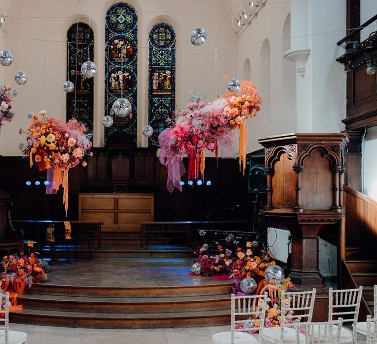 Fabrica Brighton wedding venue reception room with suspended colourful flower arrangements and suspended disco ball wedding decor 