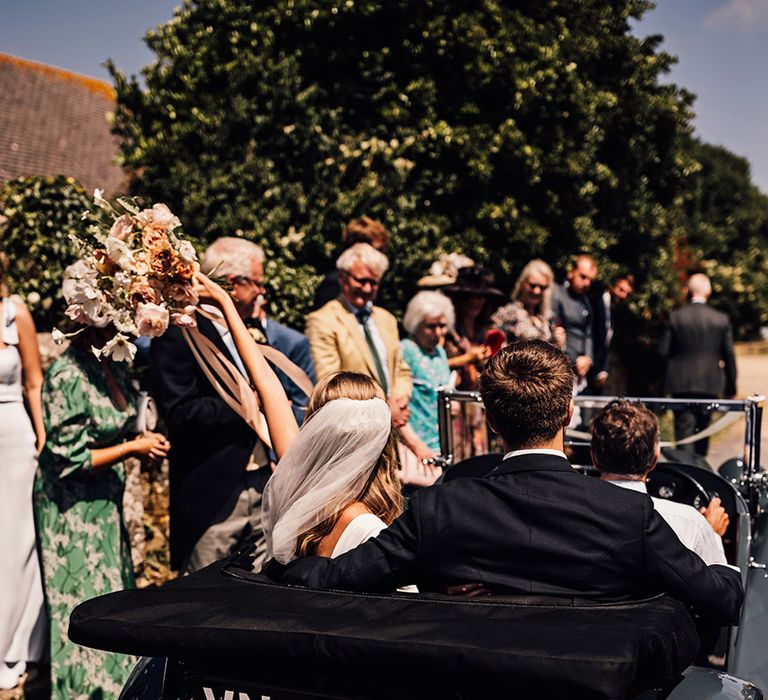 bride and groom riding in a vintage wedding car after the church wedding ceremony 