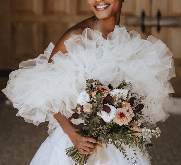 Bride in tulle off the shoulder statement wedding dress by Millia London with bridal bouquet 