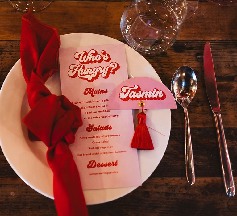 White plates with red napkin and retro style colourful wedding stationery menu and place name card 