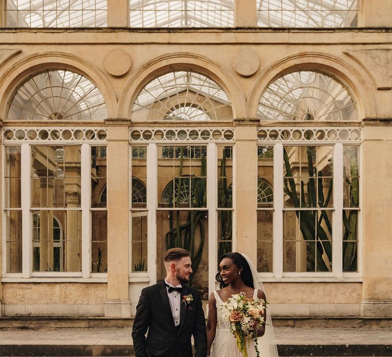 The bride and groom walk around their wedding venue as they pose for their couple portraits 