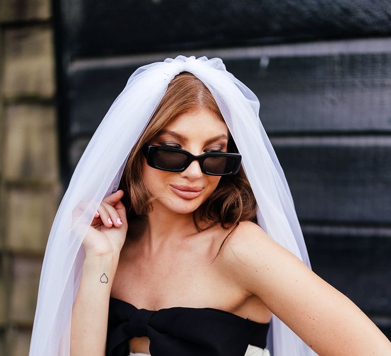 Bride in short wedding reception dress with black front bow detail