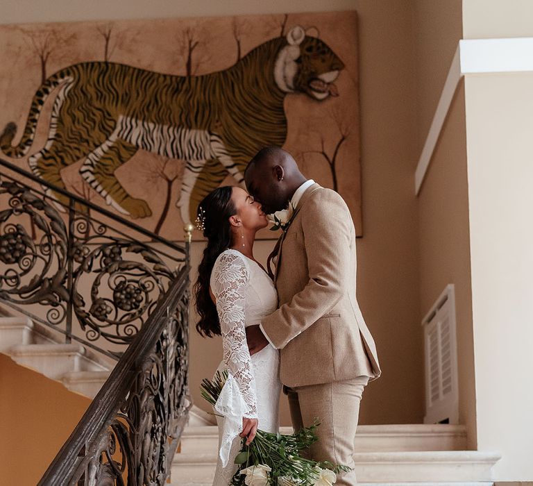 The bride wearing a long sleeve boho lace wedding dress with the groom in a beige suit at Port Lympne Wildlife Park 