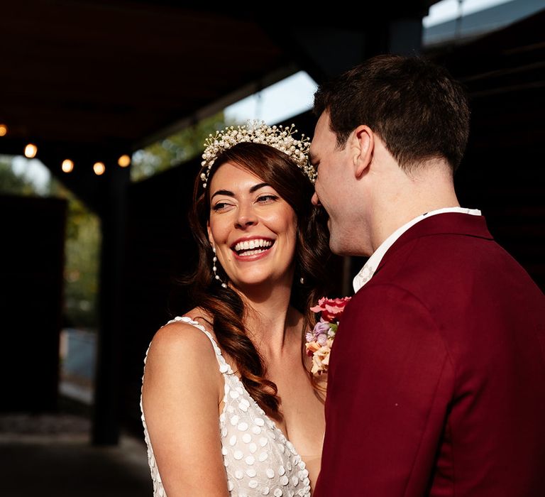 Bride wearing white bridal crown accessory smiling with the groom 