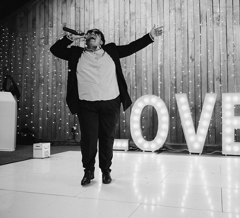 Wedding singer peforms between the wedding speeches in front of 'LOVE' letter lights 