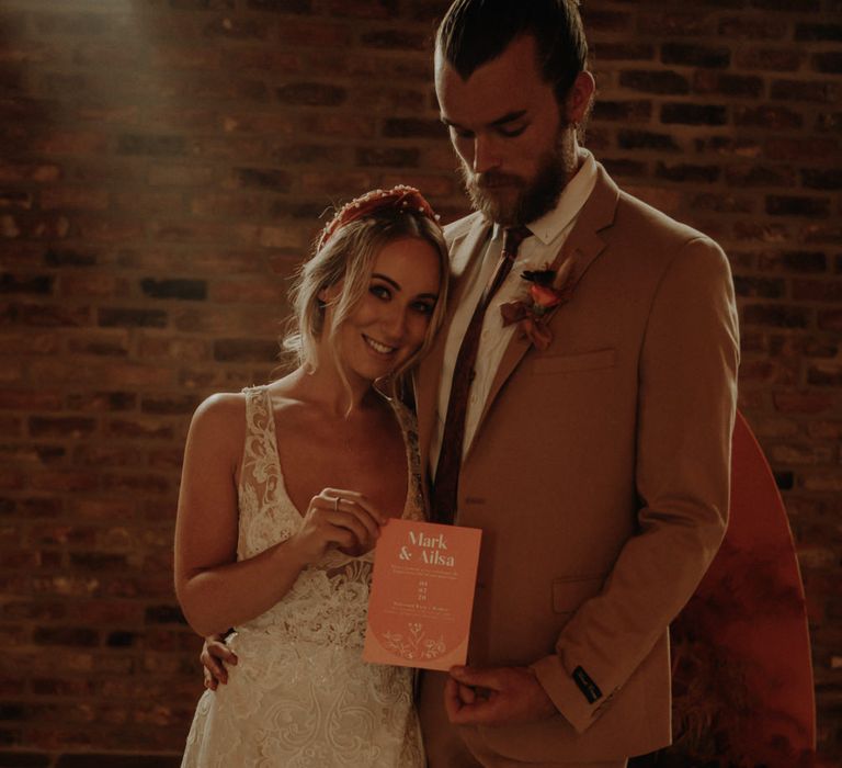 bride and groom holding an orange wedding invitation