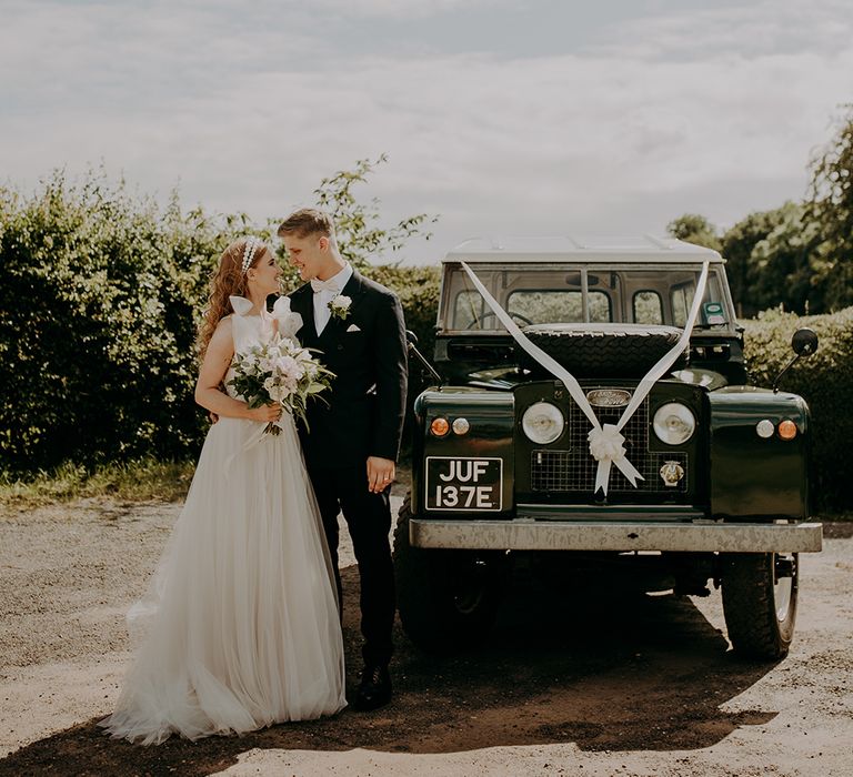 Bride and groom portrait by the wedding jeep