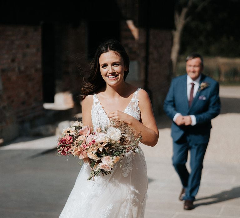 Beautiful bride in lace Madi Lane wedding dress holding her bouquet 