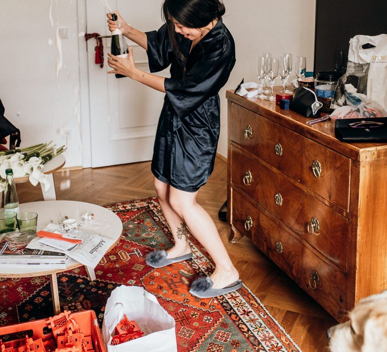 Bridesmaid popping champagne on the wedding morning 