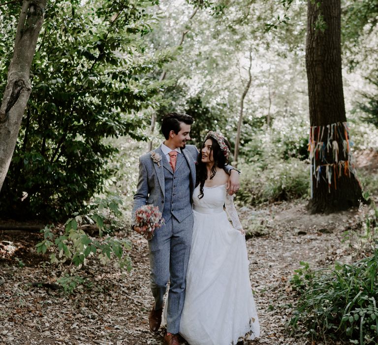 Bride and groom walk through woodland. Bride wears ASOS Bridal dress.