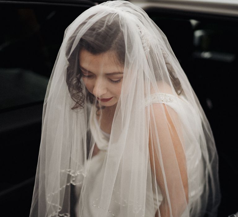 Bride leaves car with veil over her