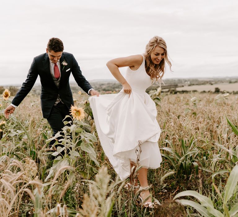 Bride in Suzanne Neville wedding dress walking through the fields 