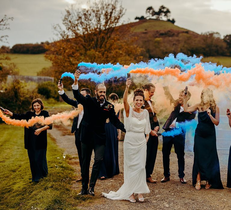 Wedding party with blue & orange smoke bombs outdoors