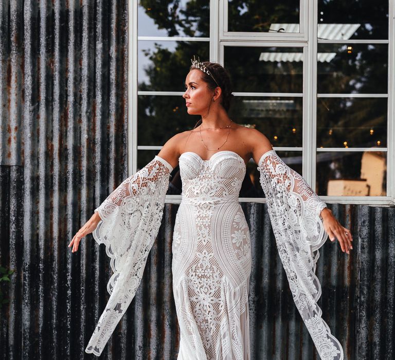 Bride spreads arms wide to show off lace sleeves 