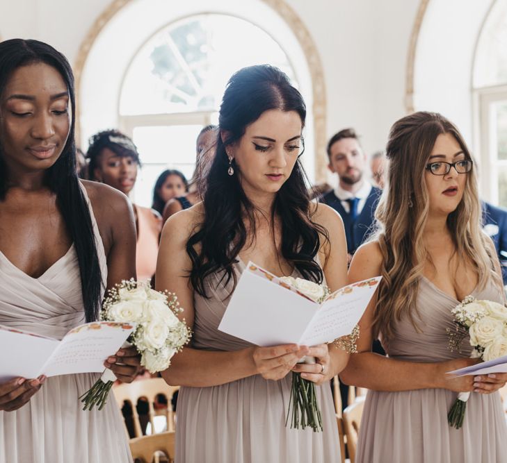 Bridesmaids in beige chiffon dresses singing during the wedding ceremony 