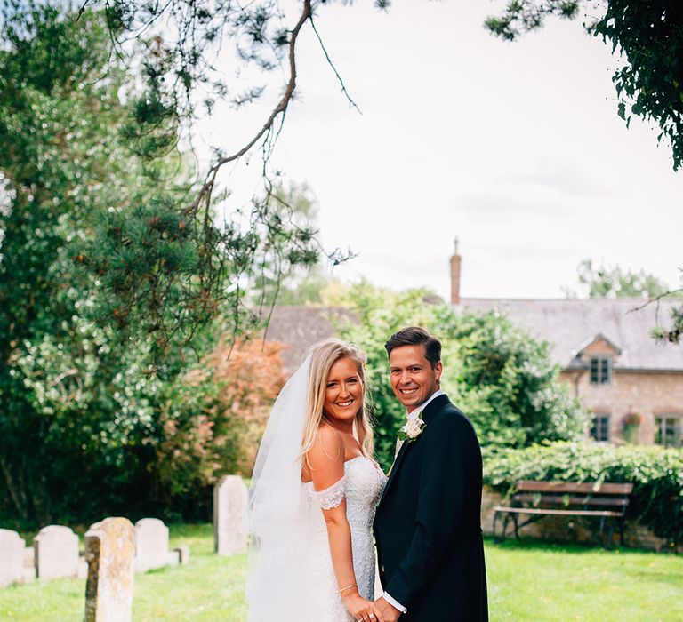 Bride and groom holding hands in church garden