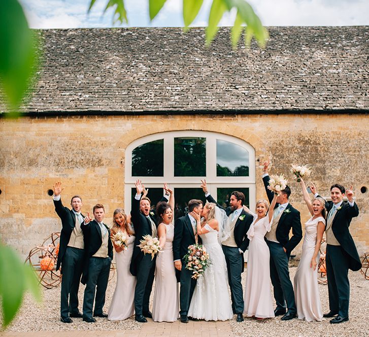 Wedding party celebrating outside barn wedding venue with peach wedding theme