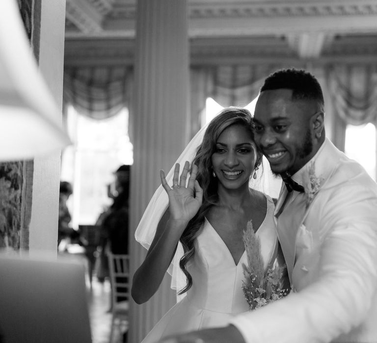 Black and white portrait of the bride and groom waving to their virtual wedding guests 