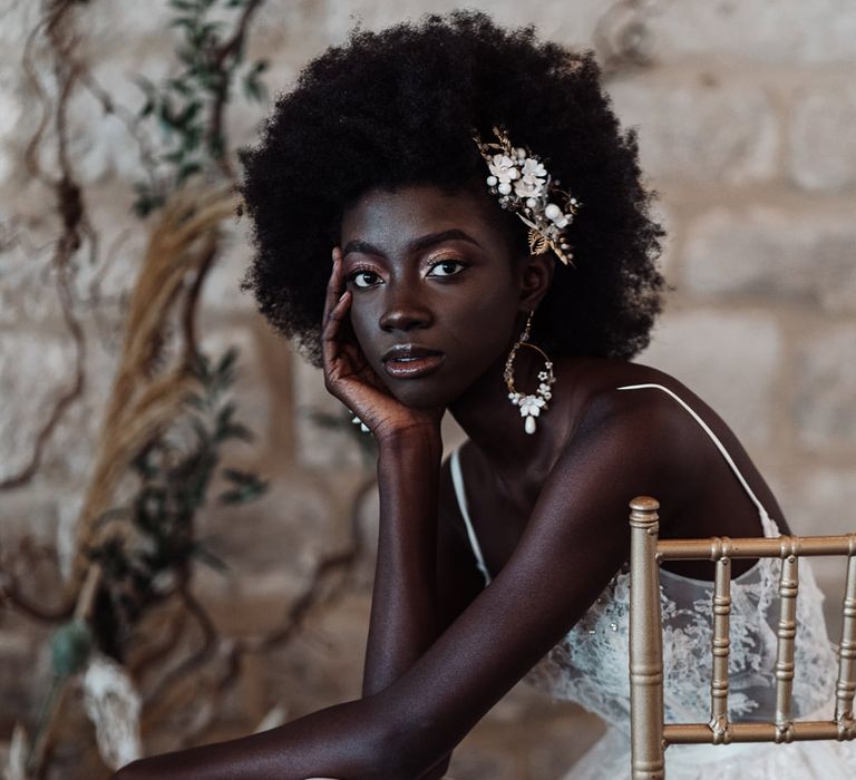 Beautiful Black bride with afro hair, hair accessory and earrings with shimmering gold eyeshadow and lipgloss 