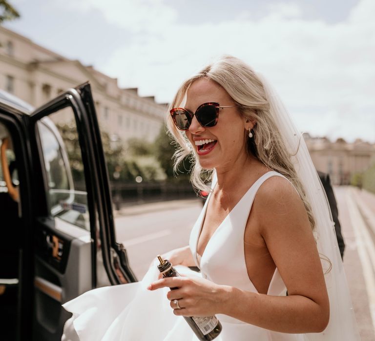 Bride laughs whilst wearing sunglasses outdoors in London