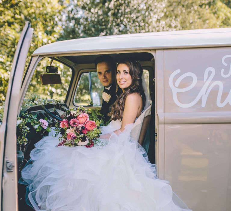 Bride and groom sat in wedding champagne camper van 