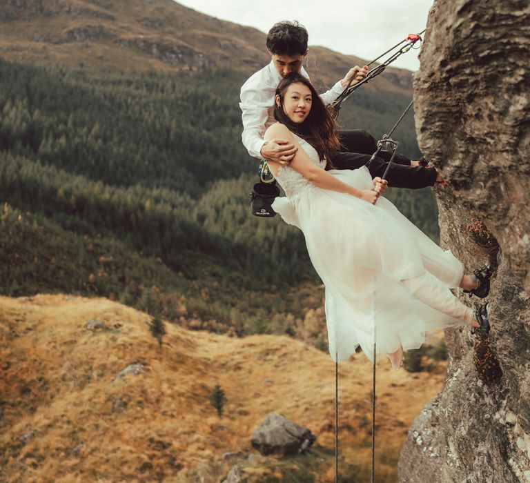 Couple suspended together during rock climbing engagement session