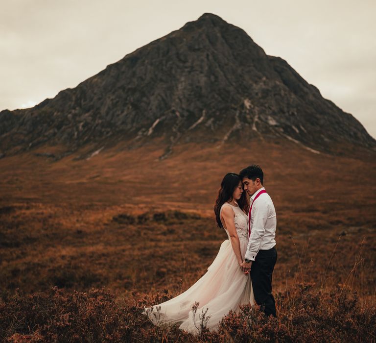 Couple stand together and hold hands in the Scottish countryside