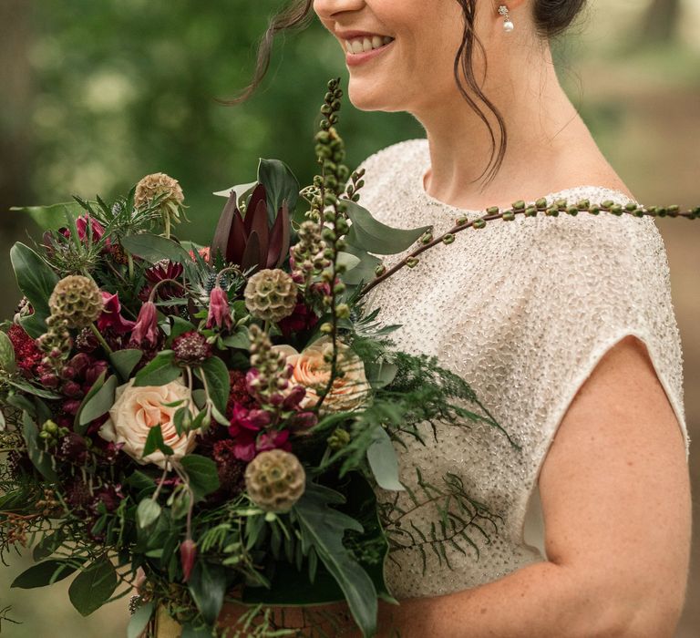 Bride carries floral bouquet and wears wedding band in her hair