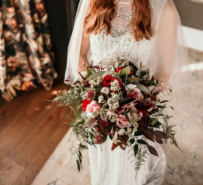 Bride wears lace wedding gown with diamanté embellishment and carries floral bouquet