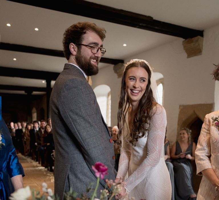 Bride and groom holding hands - bride wears beaded long sleeved bridal gown