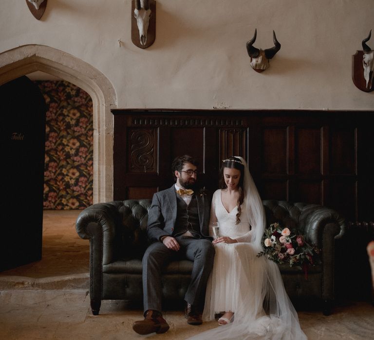 Bride and groom sat on black sofa at Brympton House Wedding 