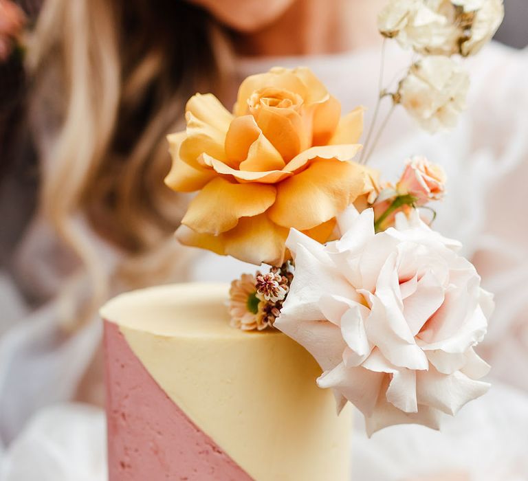 Bride holding a yellow and pink buttercream wedding cake by Sugar Plum Bakes 