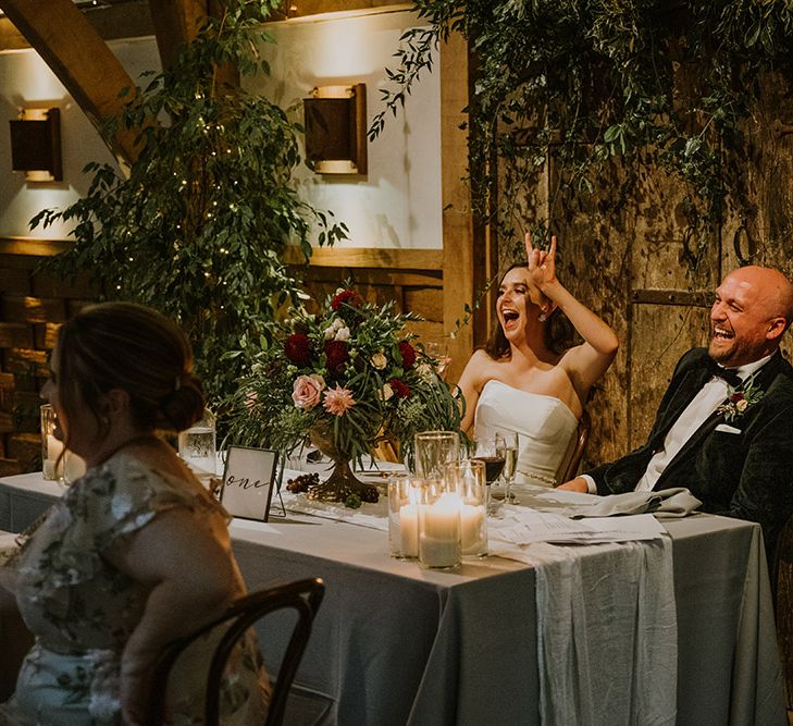 Bride and groom sitting at their sweetheart table laughing 