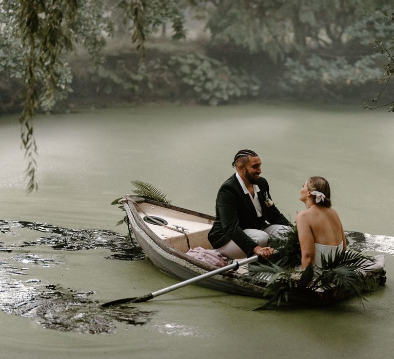 Bride and groom sailing in a rowboat on a green algae covered lake