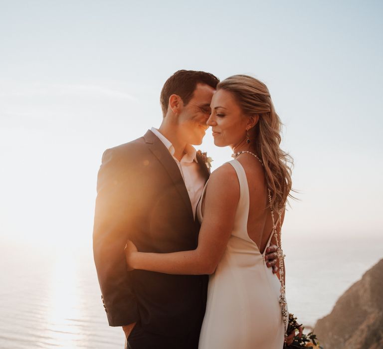 Bride & groom kiss as the sunsets behind them during golden hour in California 