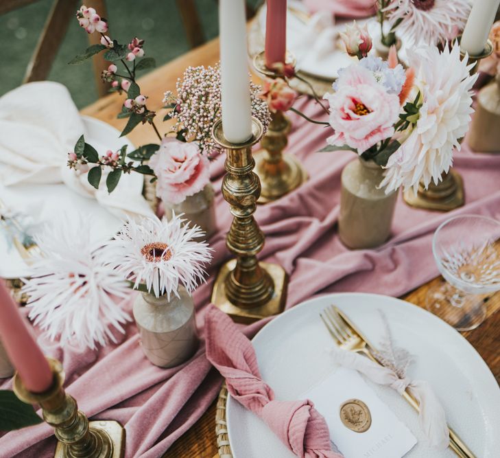 Pastel pink and gold wedding table decorations with gold cutlery and candlesticks and pink flowers and linen 