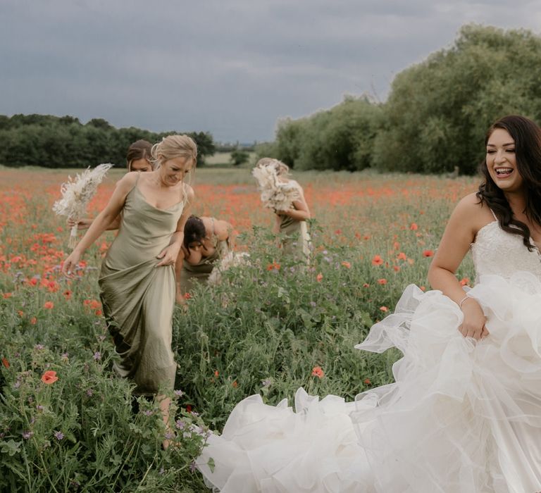 Beautiful bride walking through a poppy field holding her fishtail skirt up 