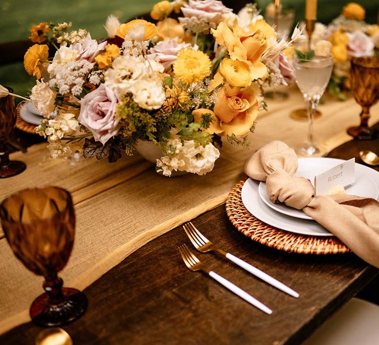 Place setting with wicker place matt and yellow flower floral centrepiece 