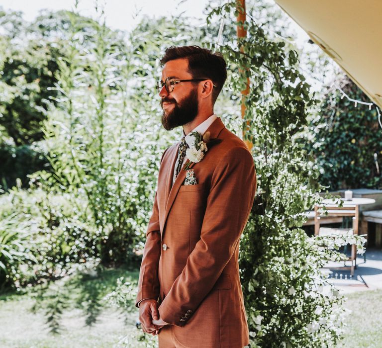 Groom awaits bride during wedding ceremony whilst wearing Topman suit in deep coral colour